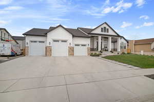 View of front of house with a porch, an attached garage, board and batten siding, a front lawn, and concrete driveway
