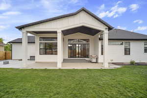 Back of property with a yard, board and batten siding, fence, a patio area, and roof with shingles
