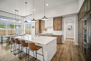 Kitchen with baseboards, a spacious island, backsplash, gas stovetop, and light countertops