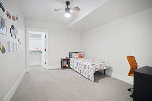 Carpeted bedroom featuring baseboards, ceiling fan, and a walk in closet