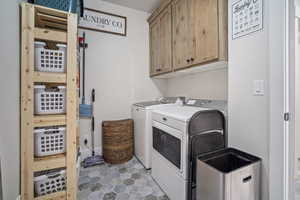 Washroom with cabinet space, separate washer and dryer, and tile patterned flooring