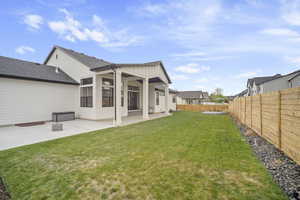 Rear view of property featuring a yard, board and batten siding, a patio area, and a fenced backyard