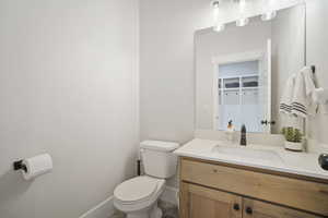 Bathroom featuring toilet, baseboards, and vanity