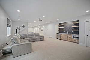 Living area with indoor wet bar, visible vents, baseboards, light colored carpet, and recessed lighting