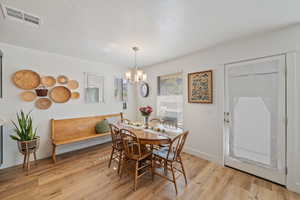 Dining area featuring an inviting chandelier, baseboards, visible vents, and light wood-style floors