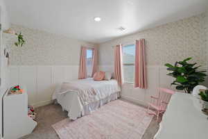 Carpeted bedroom featuring a decorative wall, a wainscoted wall, visible vents, recessed lighting, and wallpapered walls
