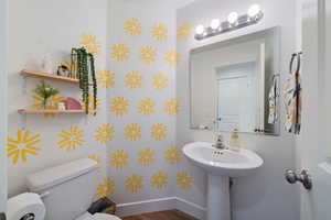 Bathroom with toilet, baseboards, and wood finished floors