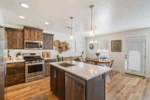 Kitchen featuring hanging light fixtures, a sink, light wood-type flooring, visible vents, and appliances with stainless steel finishes