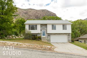 Raised ranch featuring a mountain view, driveway, a garage, and a front yard