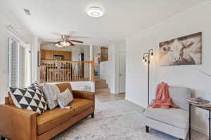 Living room with ceiling fan, stairway, ornamental molding, and baseboards
