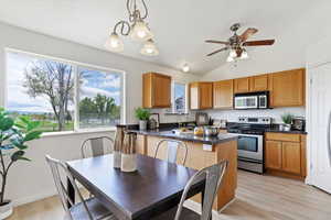 Kitchen featuring appliances with stainless steel finishes, plenty of natural light, lofted ceiling, a ceiling fan, and brown cabinetry