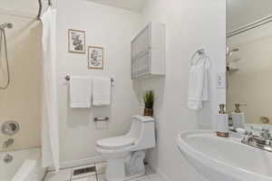 Bathroom featuring a sink, baseboards, toilet, shower / bath combo, and tile patterned flooring