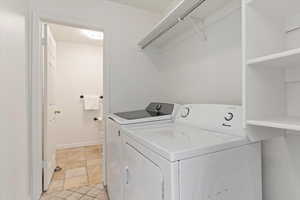 Clothes washing area featuring washing machine and dryer and baseboards