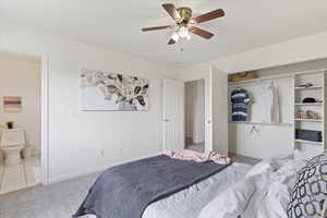 Bedroom featuring carpet, baseboards, ensuite bath, a ceiling fan, and a closet