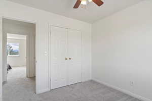 Unfurnished bedroom with carpet flooring, baseboards, a closet, and a ceiling fan