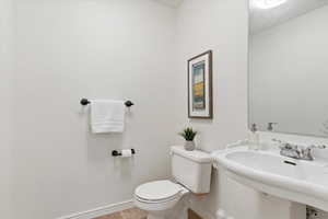 Half bathroom featuring baseboards, toilet, and a sink