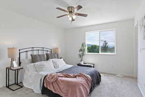 Bedroom with light colored carpet, baseboards, and a ceiling fan