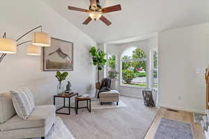 Living area with a ceiling fan, vaulted ceiling, baseboards, and wood finished floors