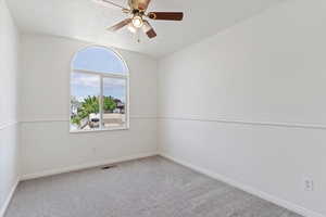 Carpeted spare room featuring ceiling fan and baseboards