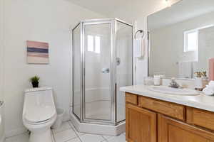 Full bathroom with tile patterned flooring, a shower stall, vanity, and toilet