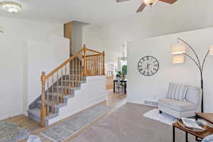 Stairs with a ceiling fan, high vaulted ceiling, baseboards, and wood finished floors