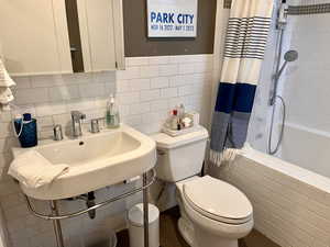 Bathroom with a sink, tile walls, tiled shower / bath combo, and toilet