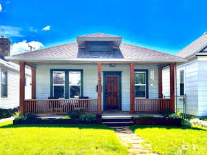 View of front of property featuring a front lawn, roof with shingles, and covered porch