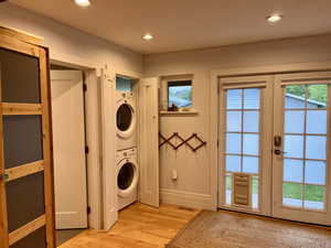 Washroom with french doors, laundry area, recessed lighting, stacked washer and clothes dryer, and light wood-style floors