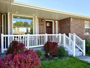 Entrance to property with a porch and brick siding