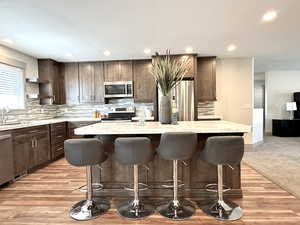 Kitchen featuring dark brown cabinets, stainless steel appliances, a sink, and a kitchen island