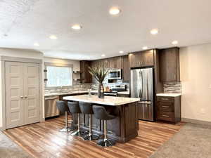 Kitchen with a sink, dark brown cabinetry, a kitchen bar, light countertops, and appliances with stainless steel finishes