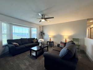 Living area with carpet floors, baseboards, and a ceiling fan