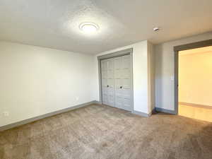 Unfurnished bedroom with baseboards, carpet flooring, a closet, and a textured ceiling