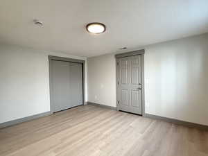 Unfurnished bedroom with a closet, visible vents, light wood-style flooring, and baseboards