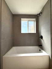 Full bathroom with walk in shower, a textured ceiling, and a bathtub