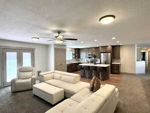Living room featuring a textured ceiling, recessed lighting, ceiling fan, dark colored carpet, and baseboards
