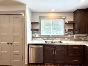 Kitchen with a sink, stainless steel dishwasher, open shelves, and dark brown cabinets