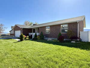 Single story home with a chimney, brick siding, fence, a garage, and a front lawn