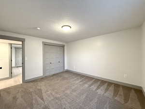 Unfurnished bedroom with baseboards, a textured ceiling, a closet, and carpet