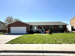Ranch-style home with brick siding, a garage, concrete driveway, a front yard, and a porch