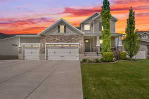 Craftsman house with board and batten siding, concrete driveway, an attached garage, stone siding, and a porch