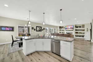 Kitchen with dishwasher, a sink, light wood-style flooring, white cabinets, and recessed lighting