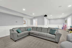Living area with wainscoting, carpet flooring, recessed lighting, and a decorative wall