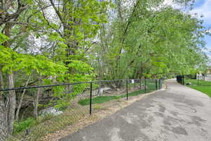 View of home's community with fence and walking path alongside creek