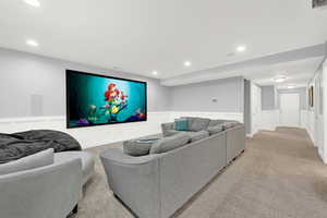 Living room with a decorative wall, wainscoting, recessed lighting, and light carpet with projector and screen.