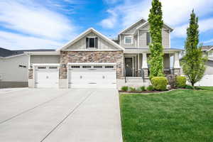 Craftsman inspired home with board and batten siding, stone siding, driveway, and a front yard