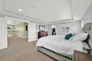 Carpeted bedroom with a raised ceiling, recessed lighting, baseboards, and multiple windows