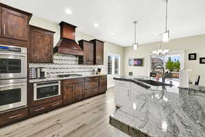 Kitchen featuring a sink, stainless steel appliances, custom range hood, healthy amount of natural light, and recessed lighting