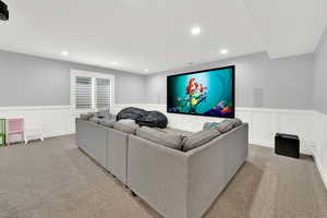 Carpeted living room featuring a wainscoted wall, a decorative wall, and recessed lighting
