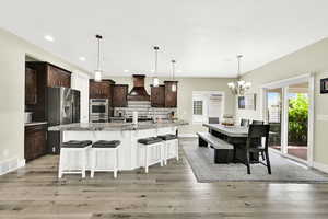 Dining room featuring healthy amount of natural light, light wood finished floors, a chandelier, recessed lighting, and baseboards